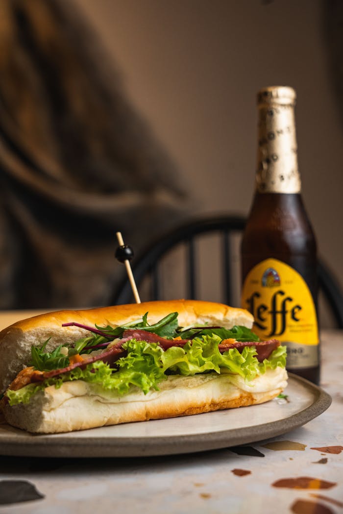 A delicious sandwich paired with a refreshing Leffe beer, perfect for a cozy meal.